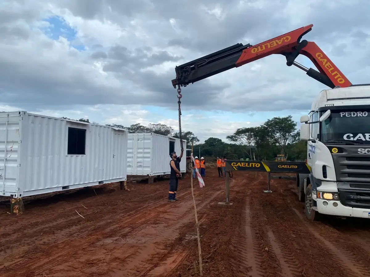Camión grúa descargando un contenedor oficina para obra